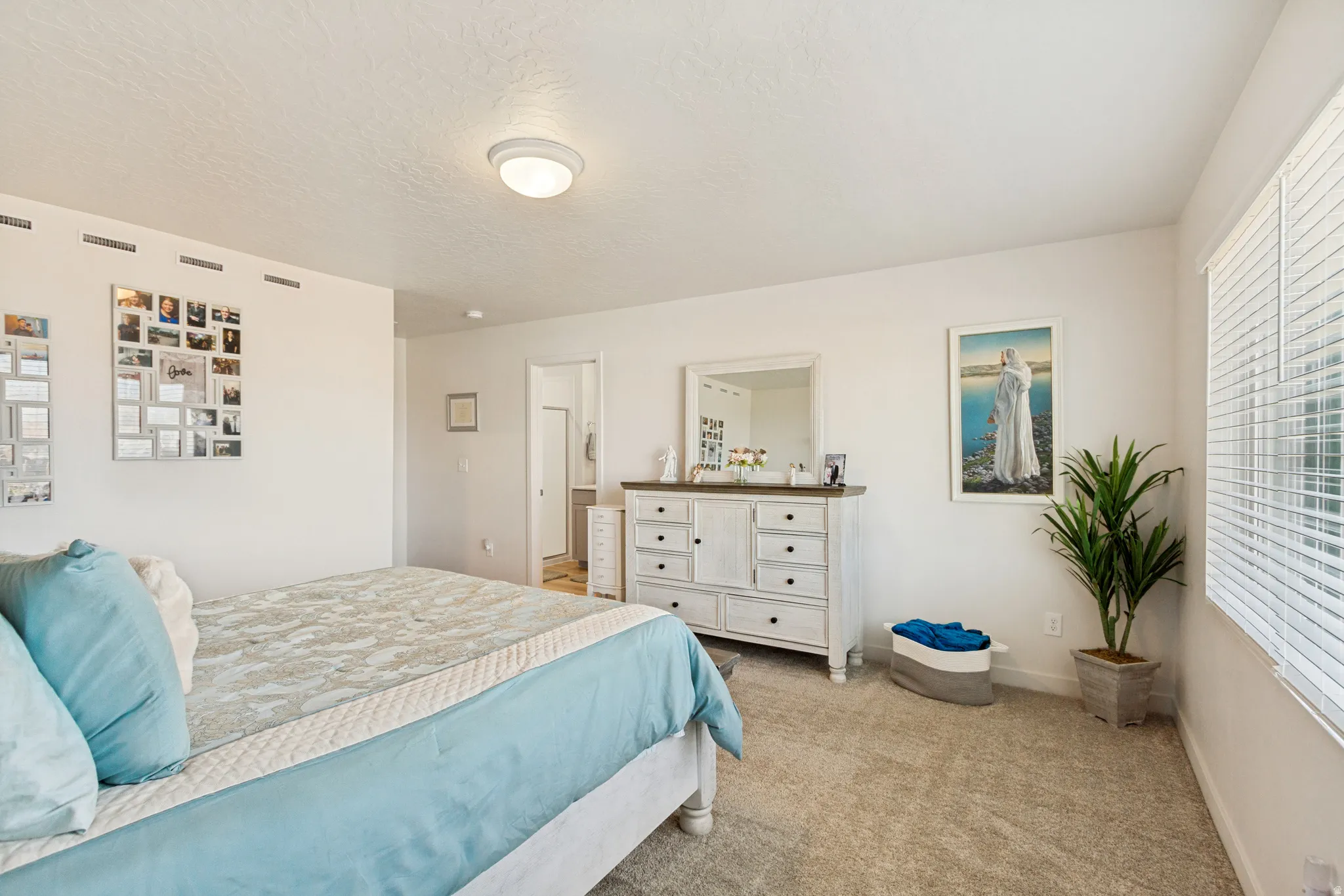 Carpeted bedroom with white walls and natural light from a window with blinds