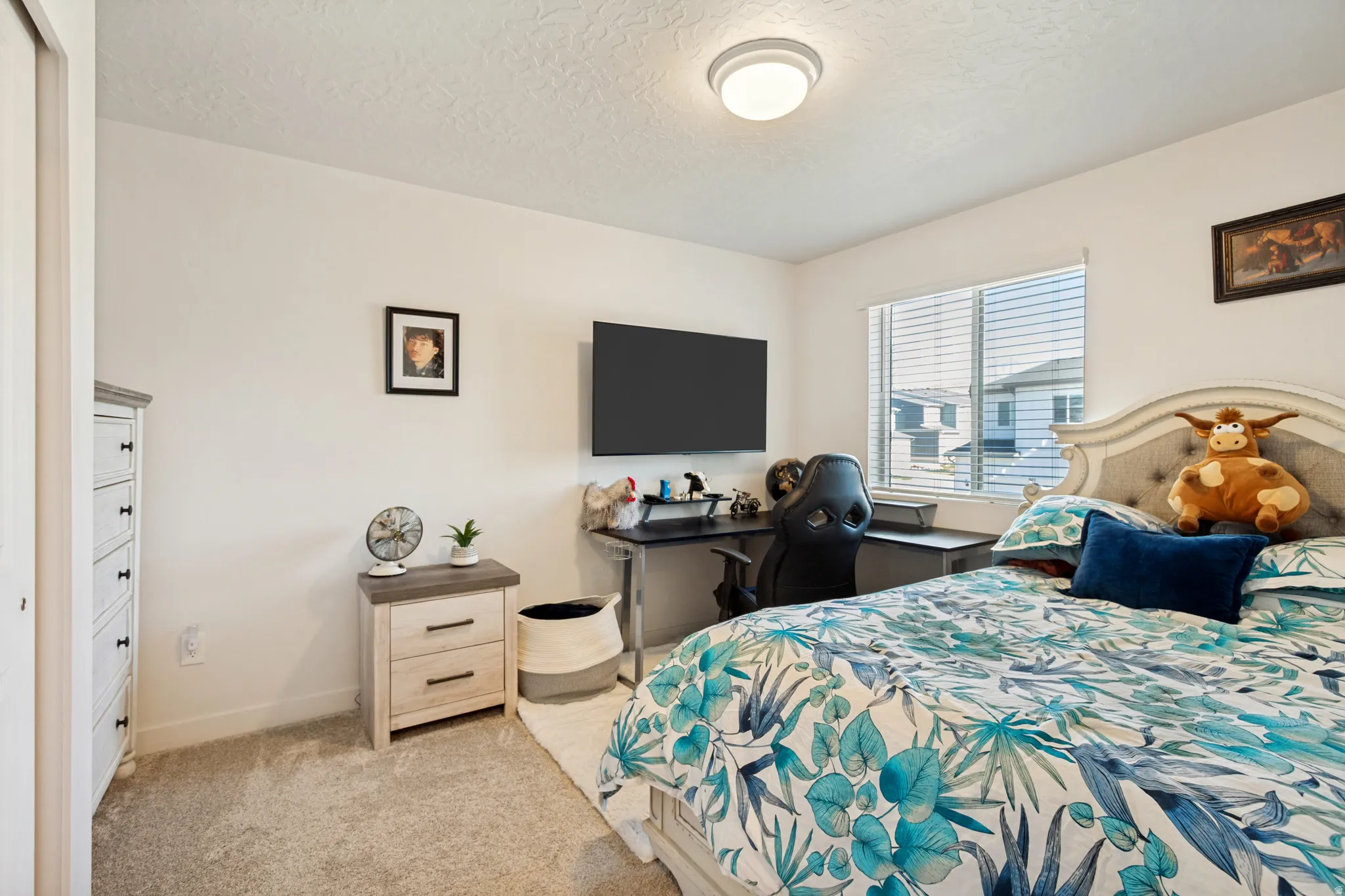 Carpeted bedroom featuring a large window with horizontal blinds, a ceiling-mounted light fixture, a built-in closet, and light-toned walls