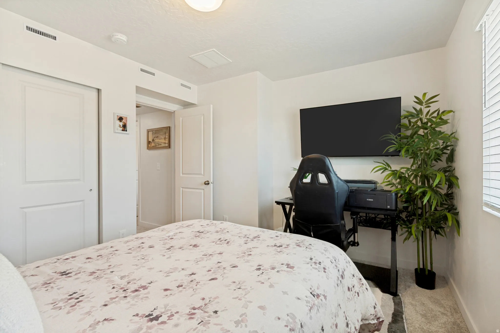 Bedroom with dual bi-fold closet doors, white interior doors, and a natural light source from a window with horizontal blinds