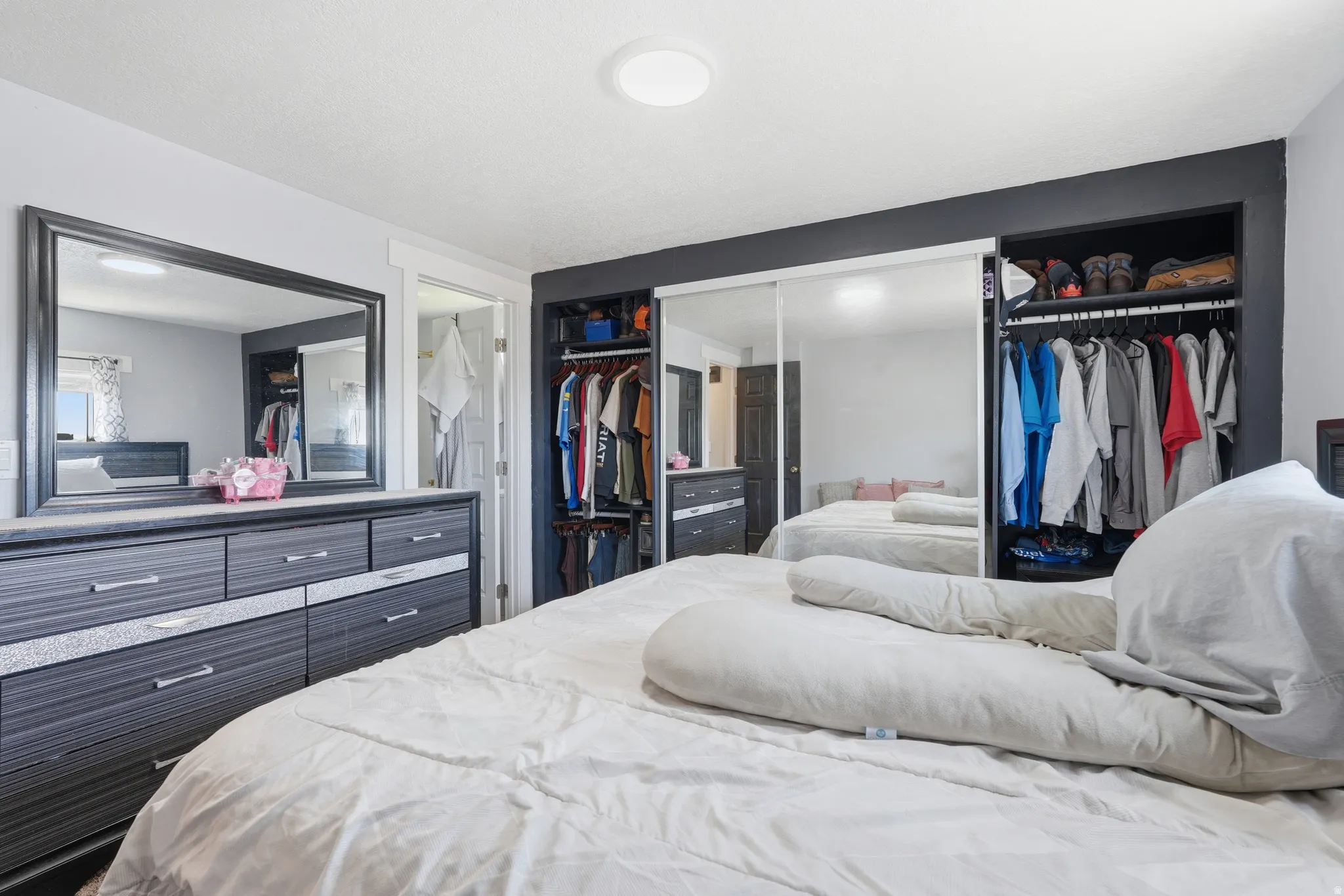 Bedroom featuring a built-in closet system with mirrored sliding doors, integrated shelving, and hanging rods