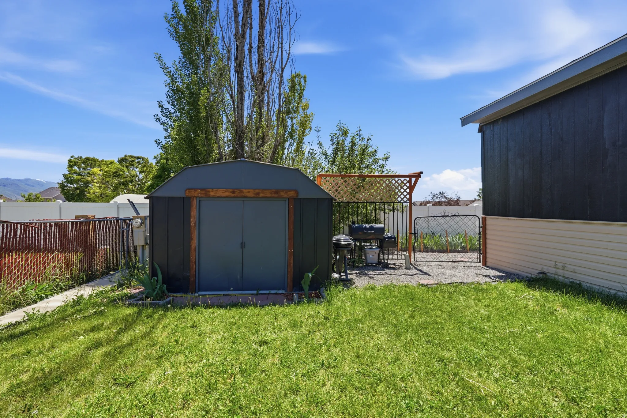 Expansive rear yard featuring a metal storage shed, gravel patio area, and perimeter fencing