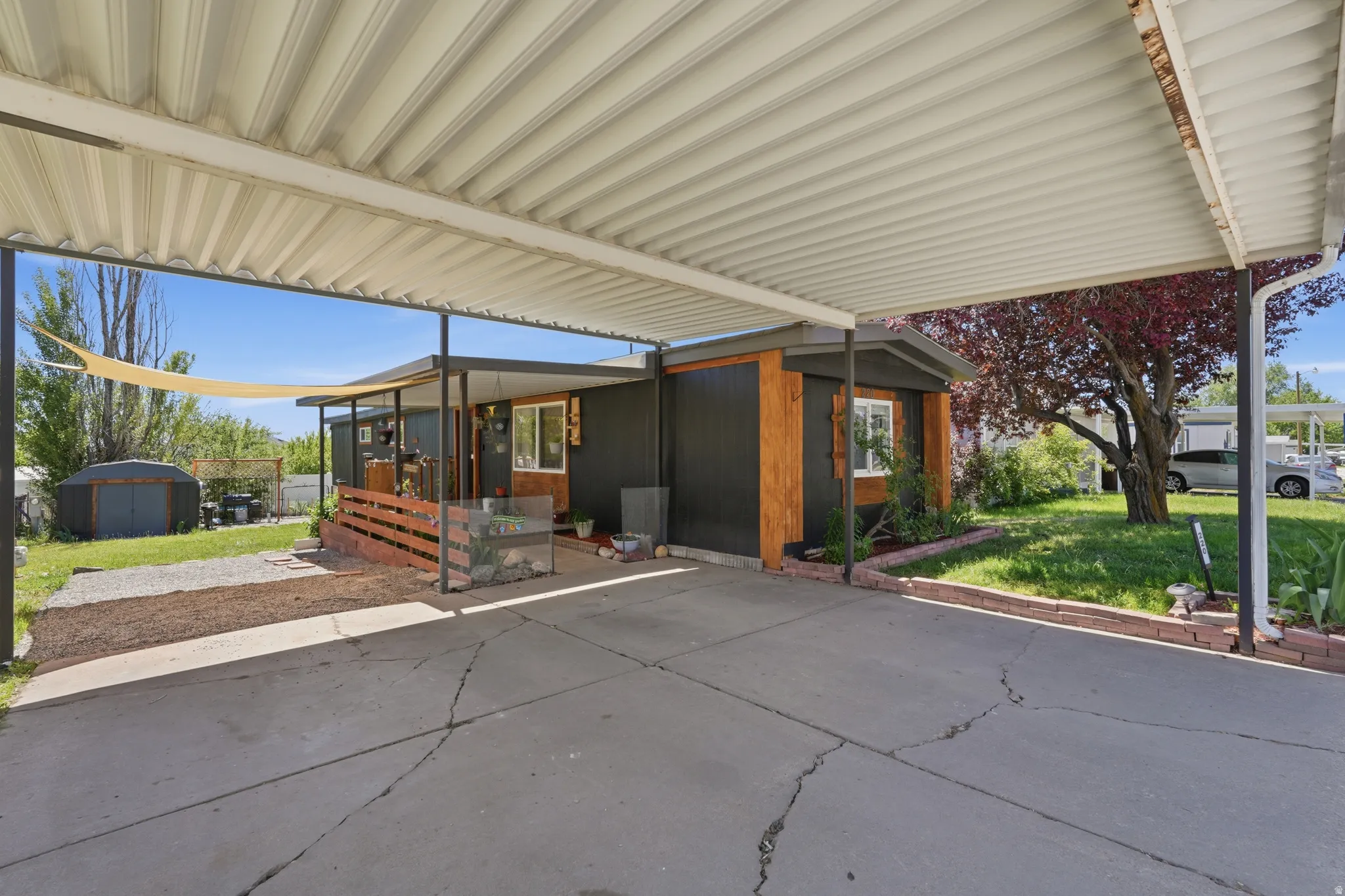 Carport offering covered parking and an exterior featuring dark panel siding with wood-finish accents