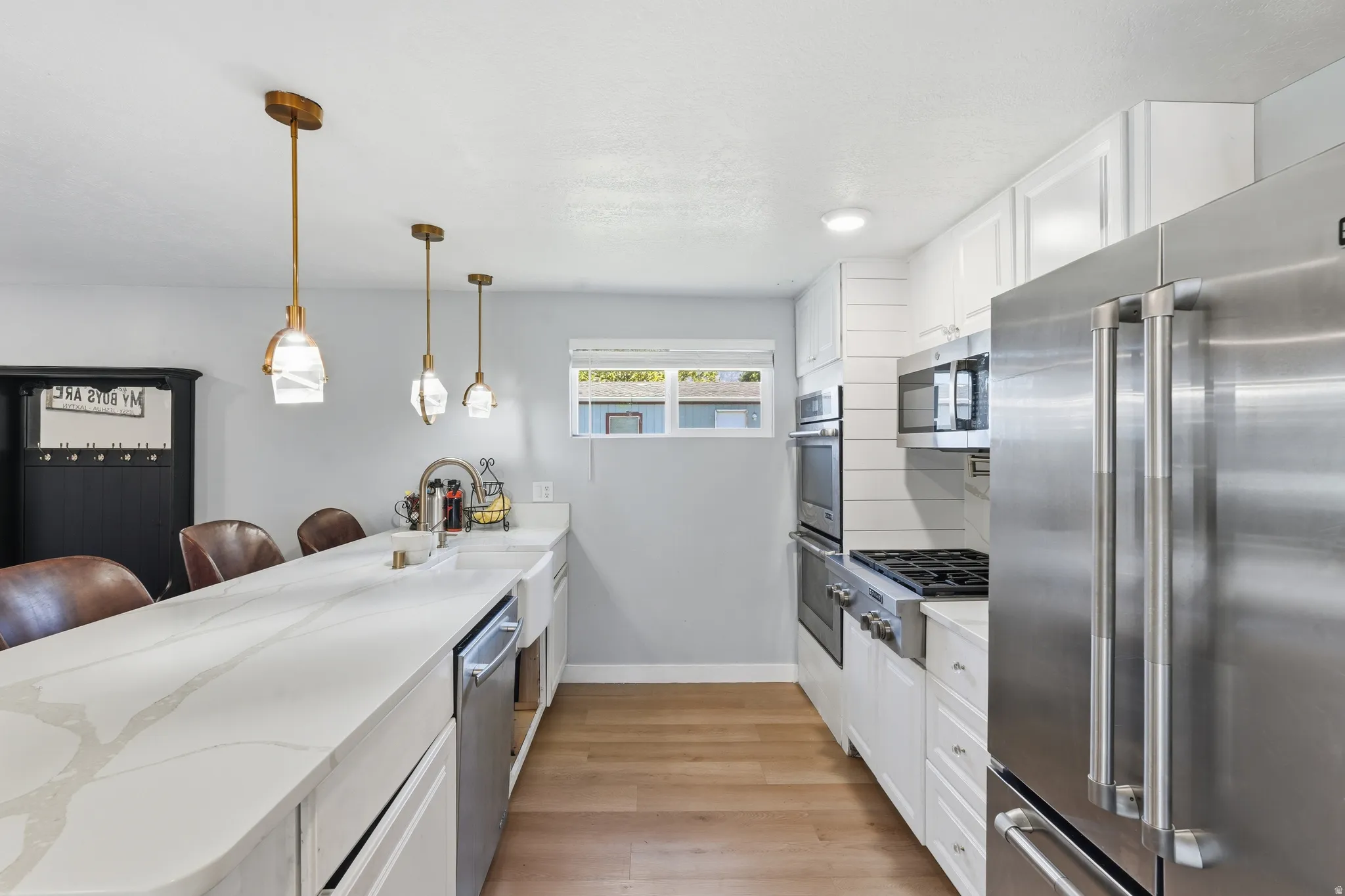 Modern kitchen featuring light wood-finish flooring, white cabinetry, and stainless steel appliances