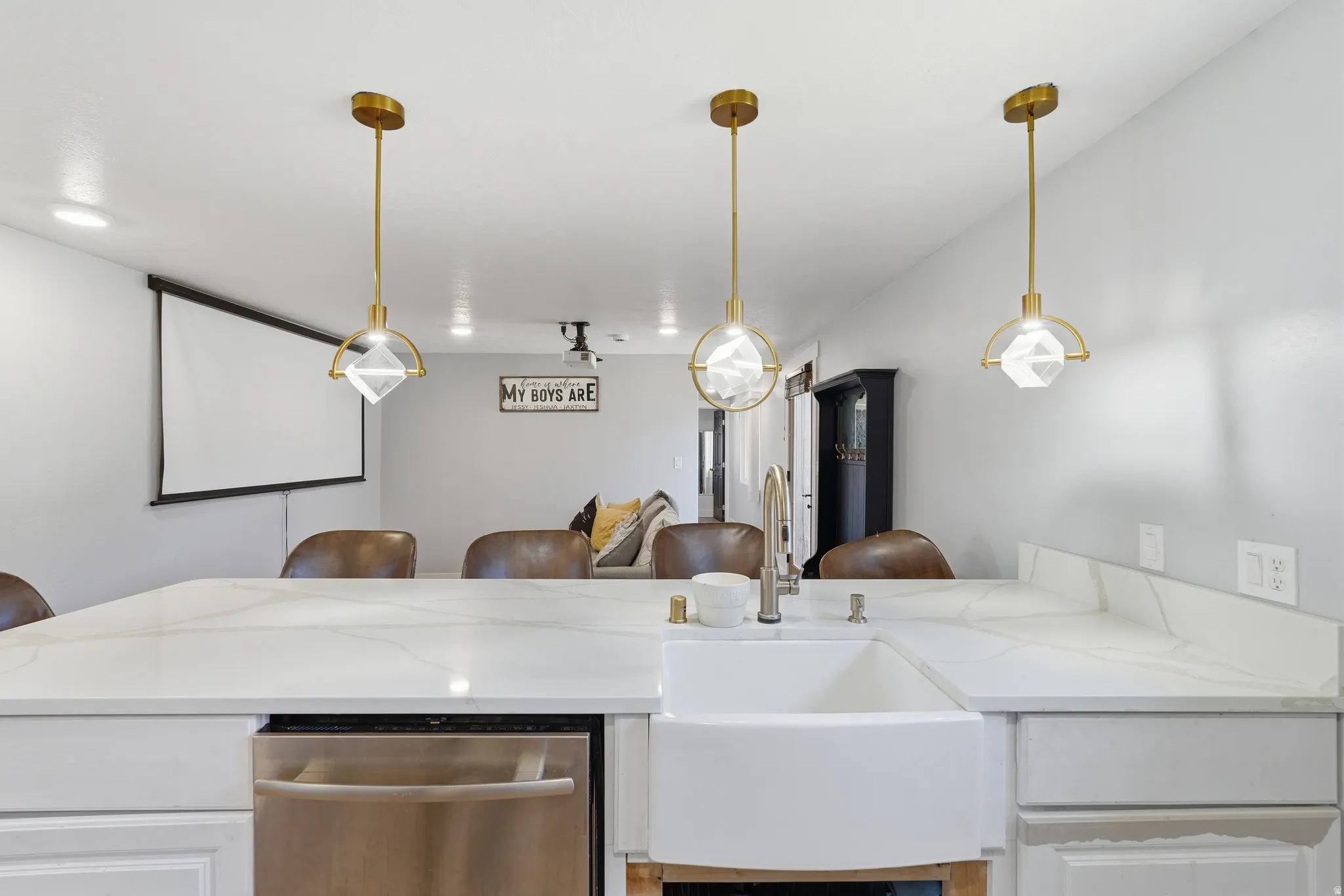 Kitchen island featuring a farmhouse sink, stainless steel dishwasher, and a white countertop with integrated backsplash