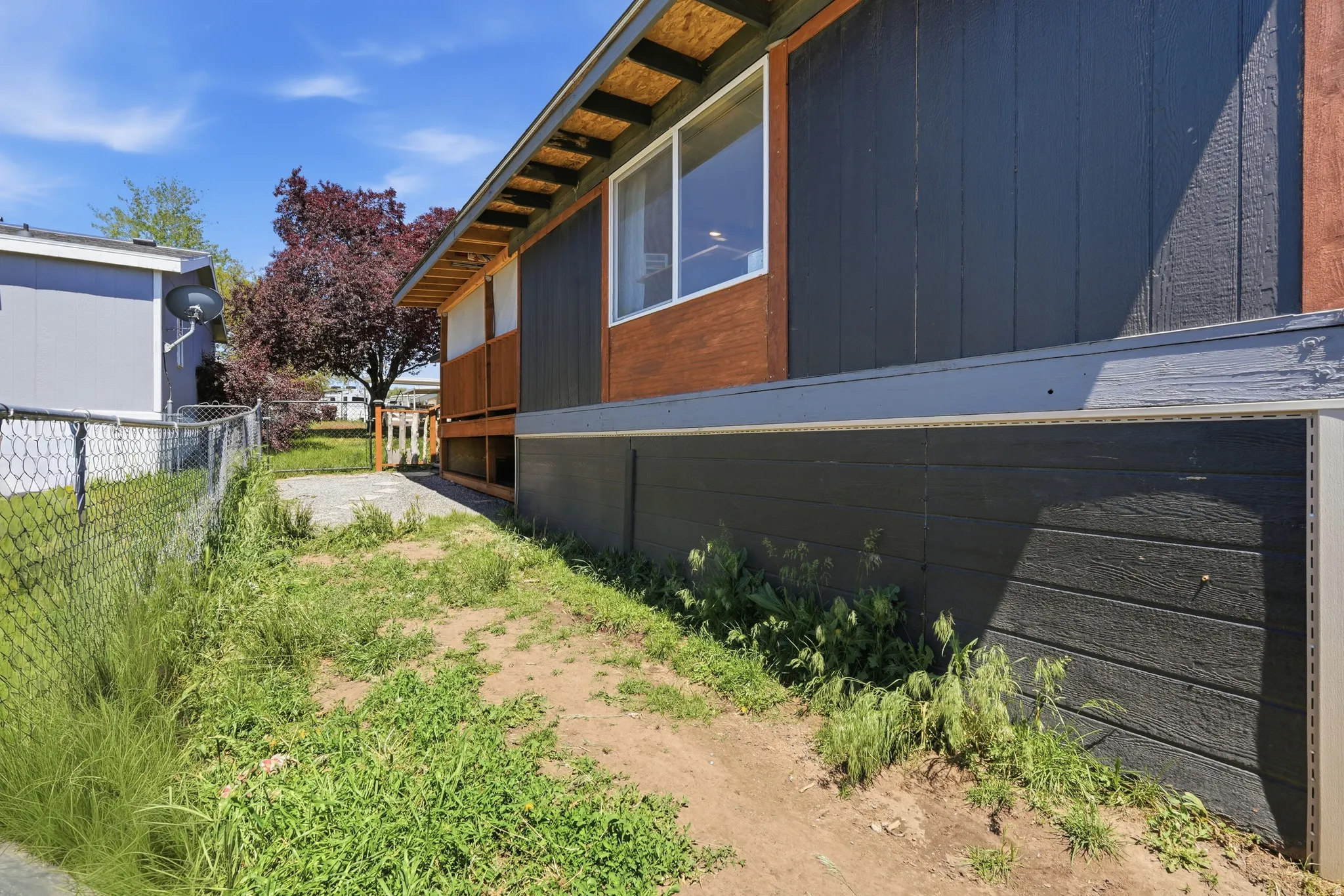 Exterior featuring dark vertical siding, wood-finish accents, and an exposed rafter tail roofline