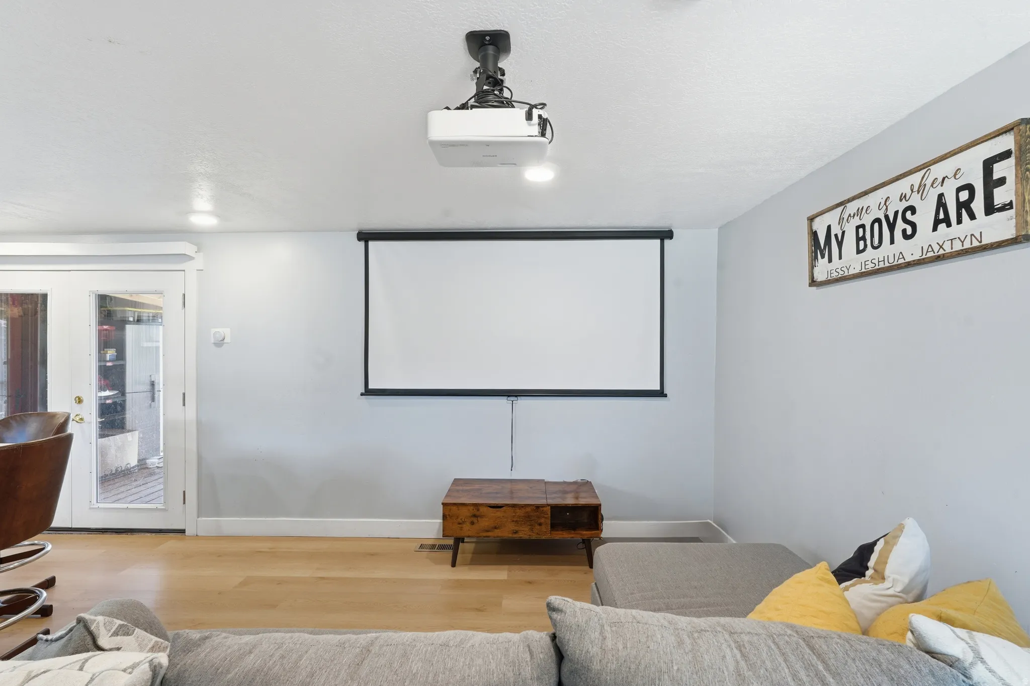 Entertainment space featuring a ceiling-mounted projector, a retractable screen, and recessed lighting