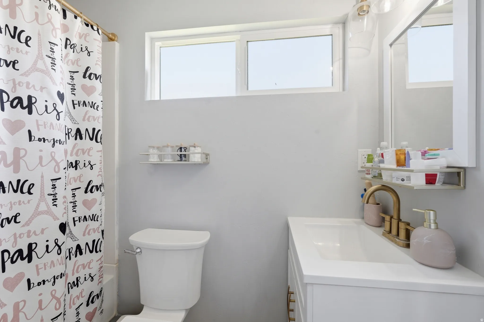 Bathroom featuring a single vanity with a white countertop and integrated sink, a two-piece toilet, and a white framed mirror