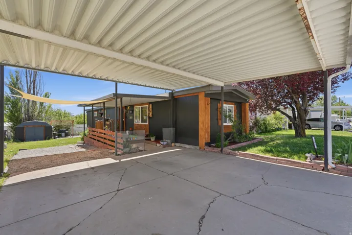 Carport offering covered parking and an exterior featuring dark panel siding with wood-finish accents