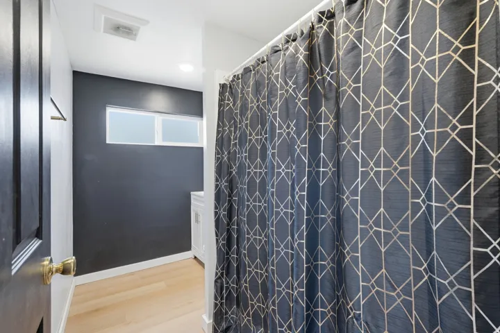 Bathroom featuring a shower with a patterned curtain, light wood-finish flooring, a contemporary vanity, and high horizontal windows