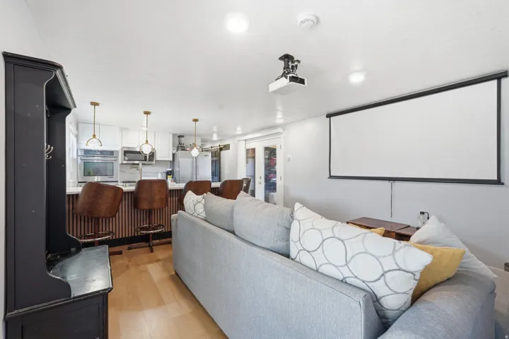 Open-concept living space featuring a built-in projector and screen, light wood-finish flooring, and white walls