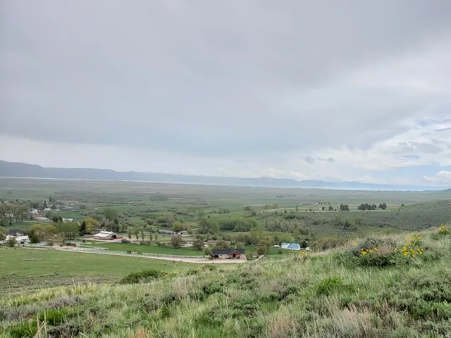 Expansive hillside property featuring natural vegetation and distant valley landscape with scattered residential structures