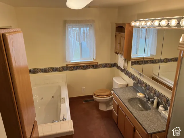 Bathroom featuring a built-in jetted tub with separate shower, wood-finish vanity, large mirrored medicine cabinet, and a window with natural light