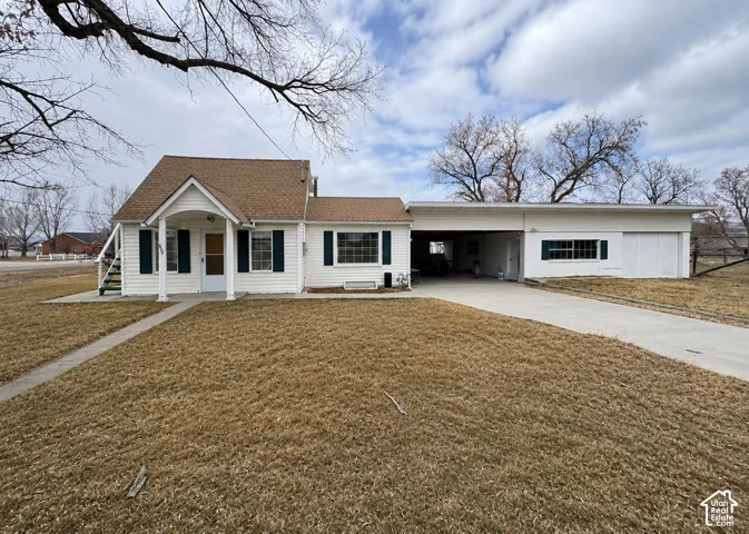 Traditional-style home featuring white siding, dark shutters, a covered entry porch, a multi-car driveway, and an attached carport