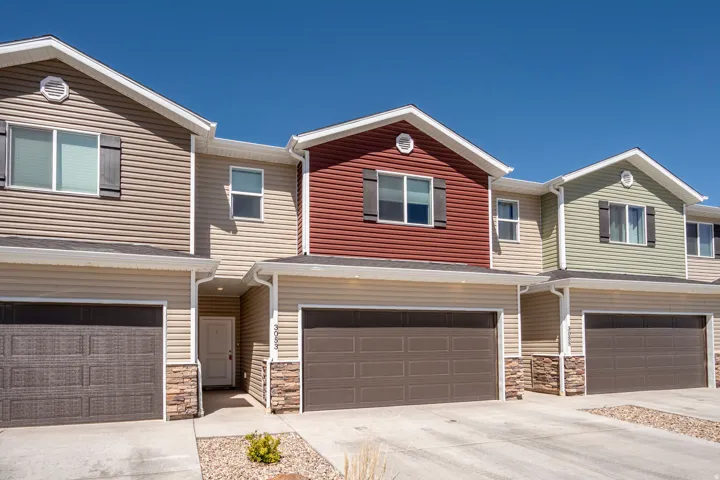 Contemporary multi-level townhome featuring a neutral-toned facade with varied siding colors