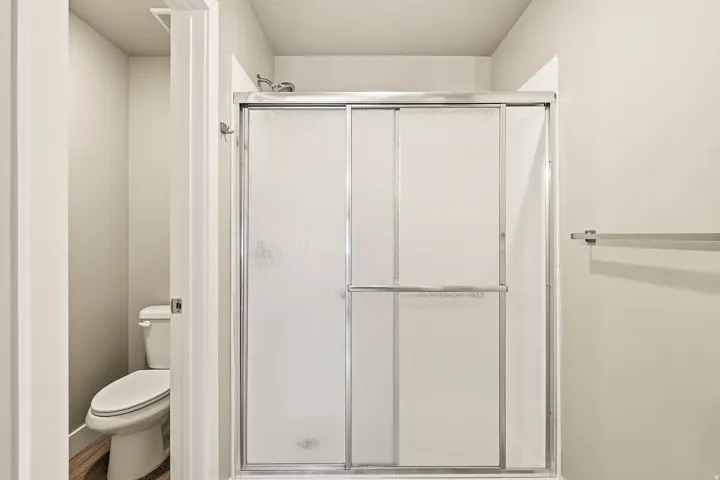 Enclosed shower with frosted glass sliding doors and a chrome shower head
