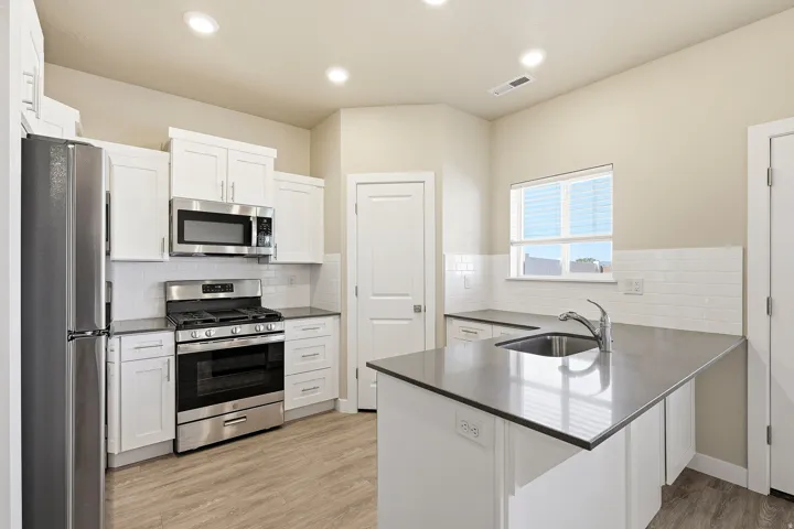 Modern kitchen featuring white shaker cabinetry, stainless steel appliances, a subway tile backsplash, and a central island with an undermount sink