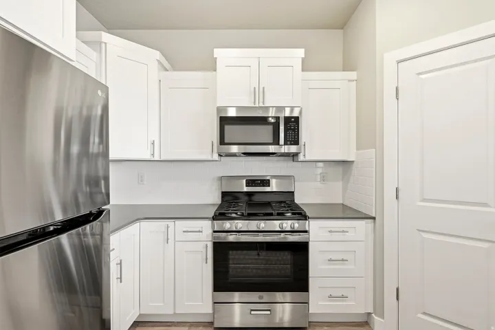 Kitchen featuring white shaker-style cabinetry, stainless steel appliance suite, dark countertops, and white subway tile backsplash