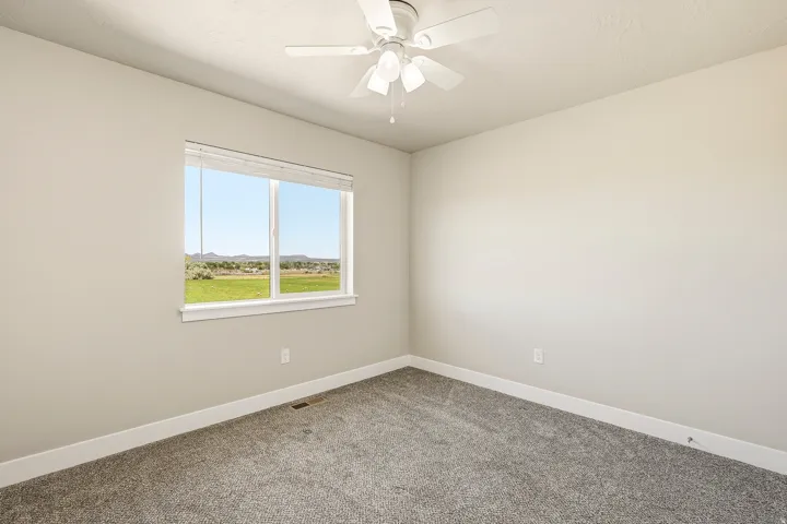 Room featuring neutral-toned walls, grey carpet, and a ceiling fan