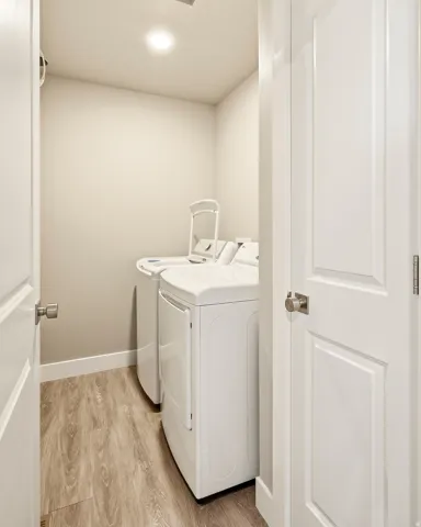 Dedicated laundry space featuring wood-finish flooring, light neutral wall tones, and white trim