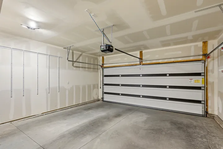 Spacious garage featuring a concrete floor, overhead lighting, and an automatic garage door opener