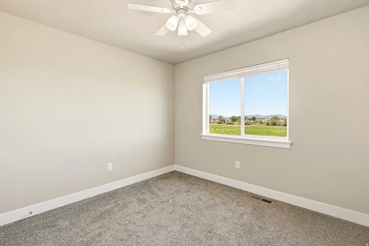 Room featuring neutral painted walls, gray carpet flooring, and a white ceiling fan with light fixture