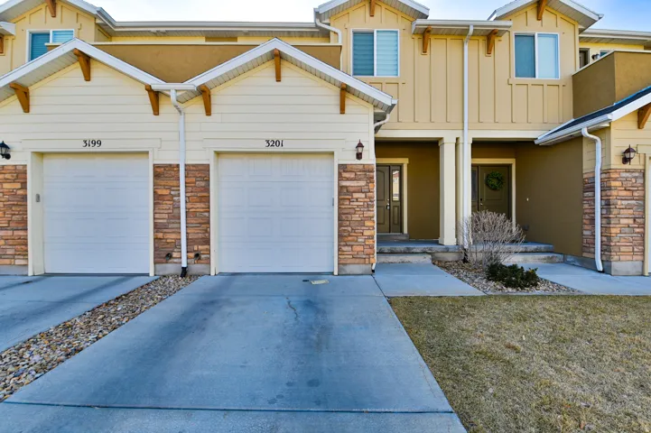 Townhome exterior featuring varied siding materials, stone accents, and two individual garages