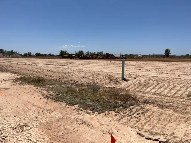 Expansive undeveloped lot featuring a clear, level terrain and a visible utility marker