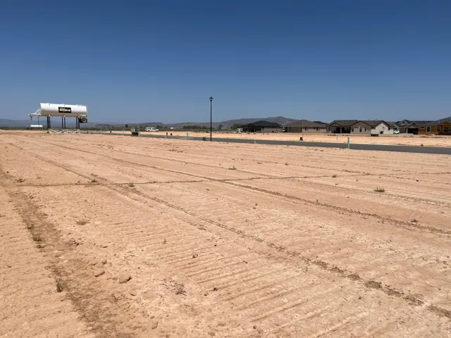Expansive cleared land parcel featuring raw earth, a paved road, and a streetlamp
