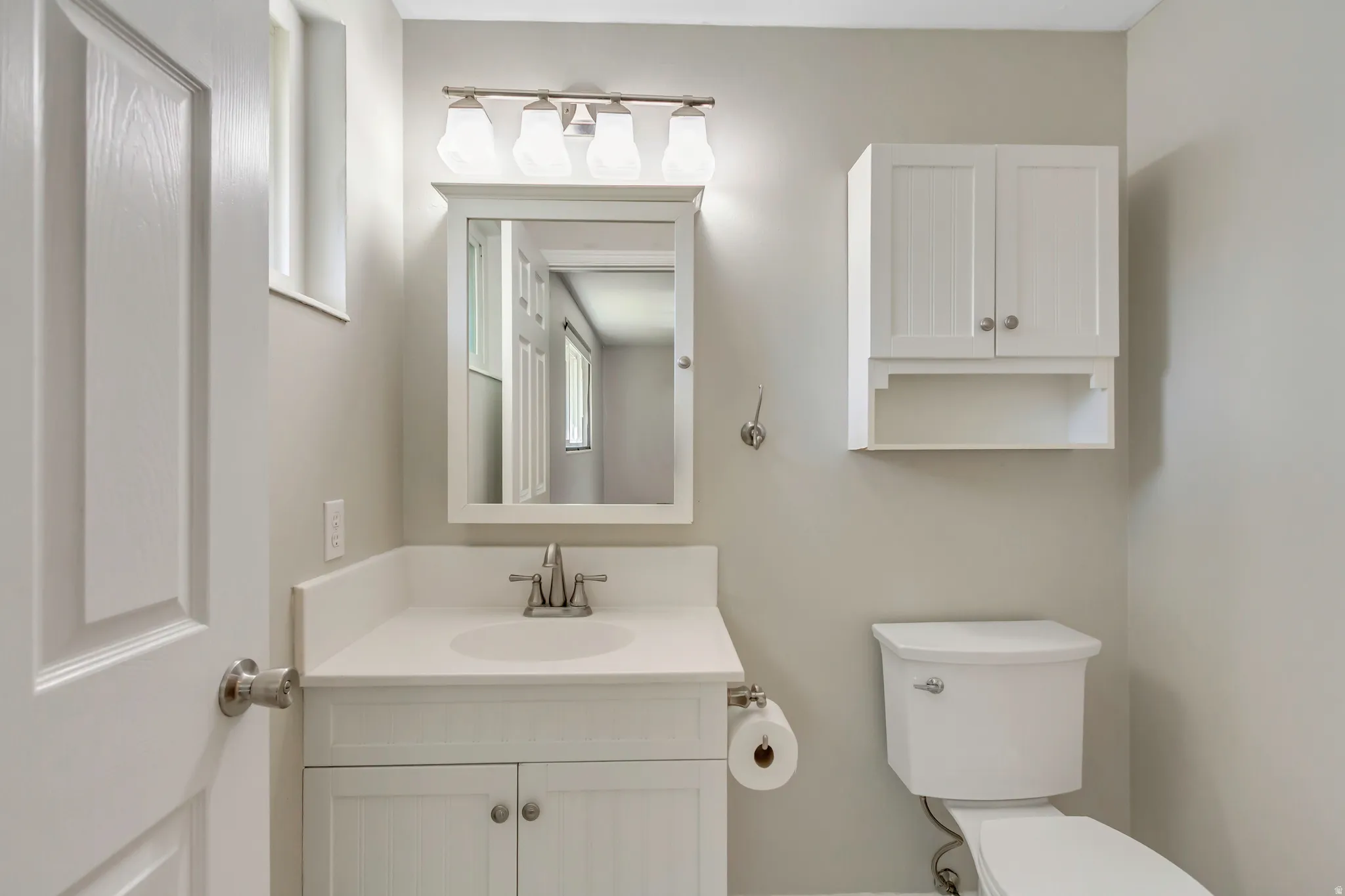 Bathroom featuring a white vanity with integrated sink, brushed nickel faucet, and a wall-mounted medicine cabinet