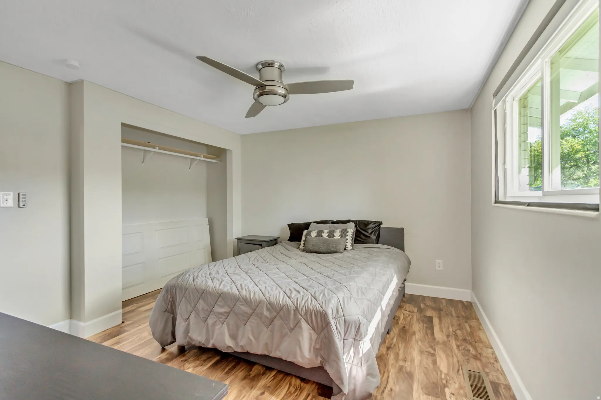 Bedroom featuring wood-finish flooring, a ceiling fan, and a built-in closet with shelving and hanging rod
