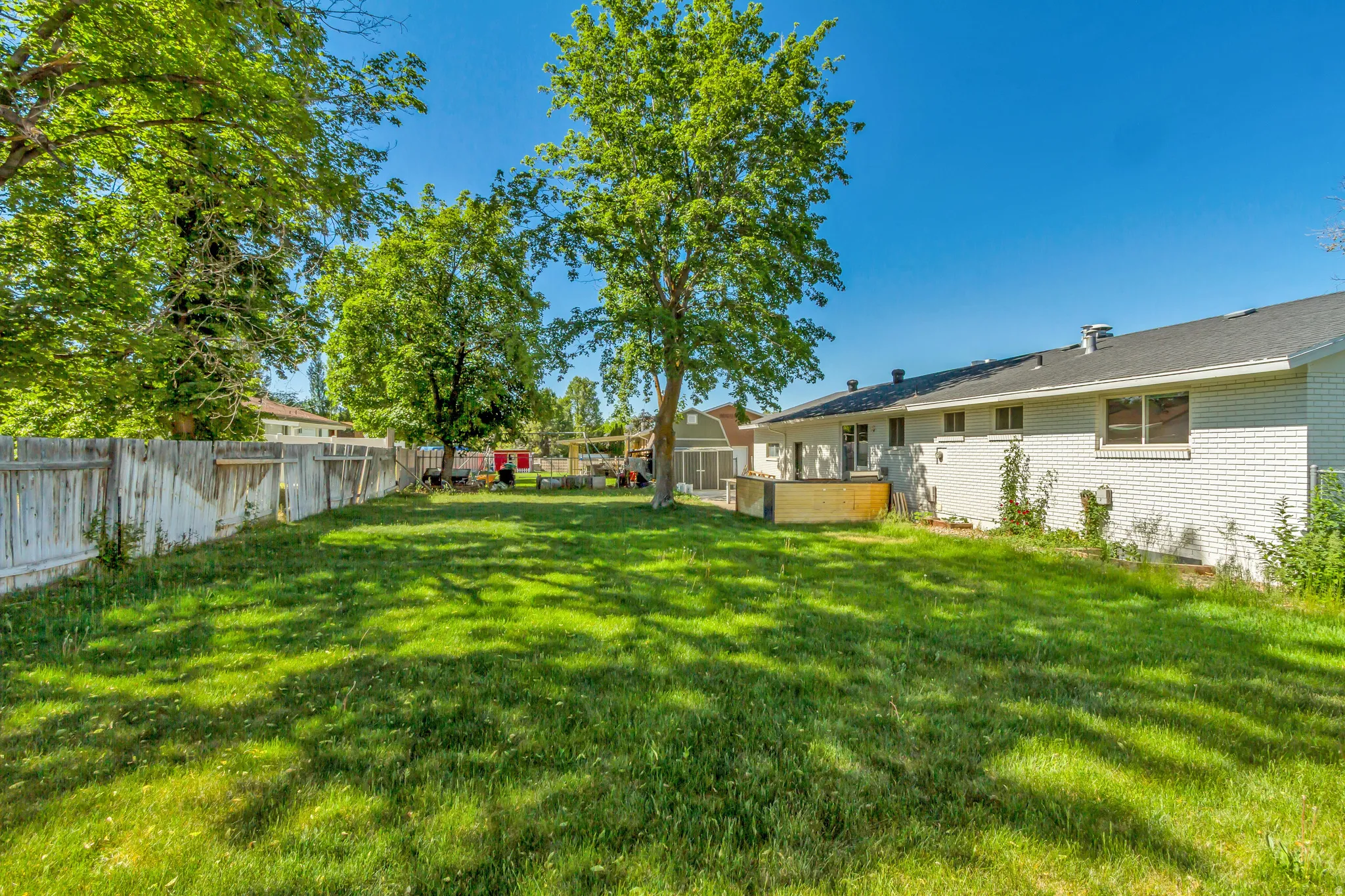 Expansive green lawn with mature trees and perimeter fencing