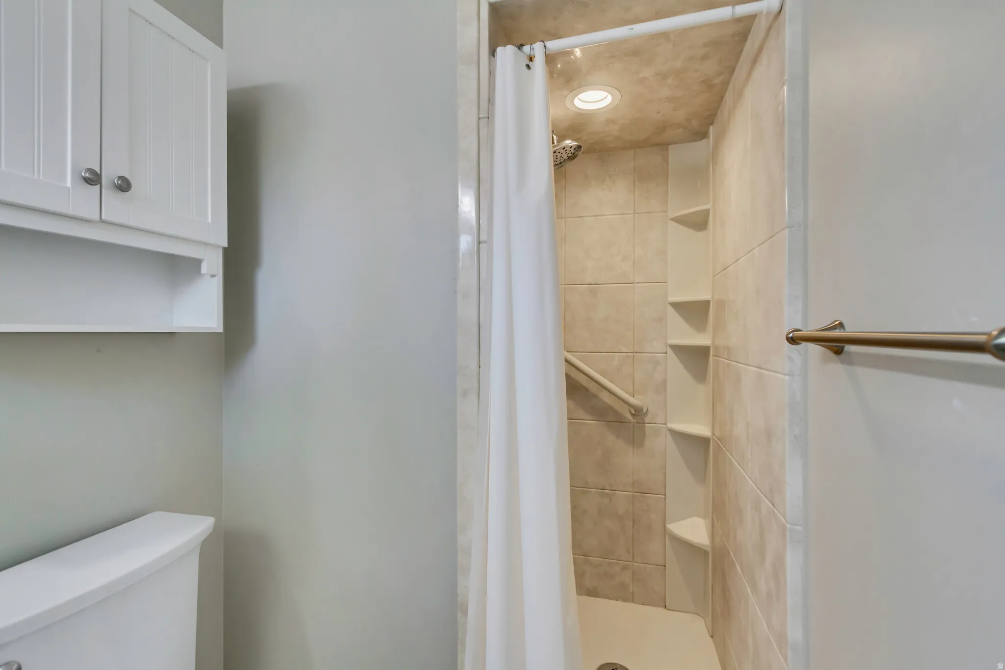 Tiled walk-in shower with a recessed light fixture and integrated corner shelving