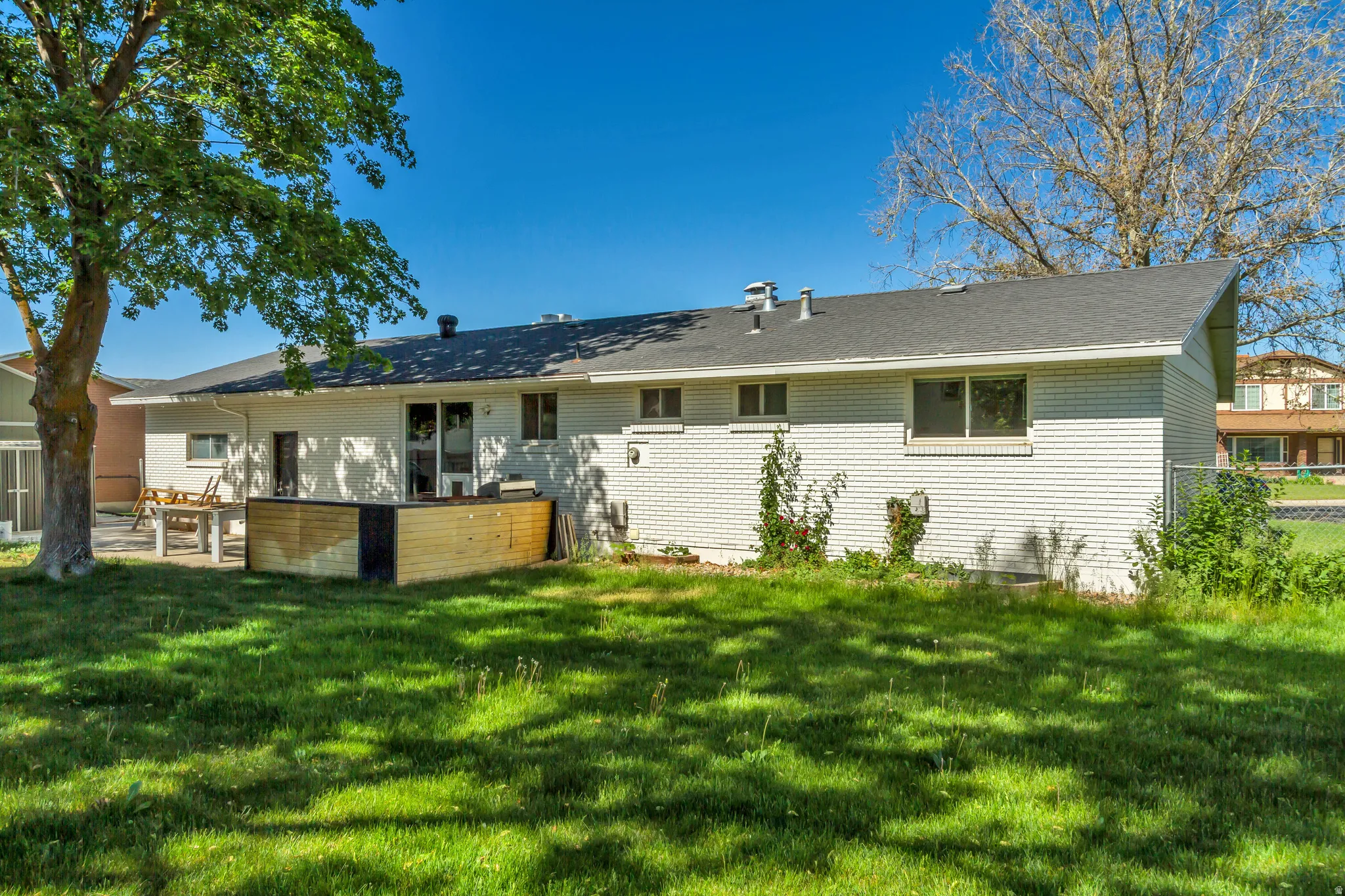 Rear exterior featuring white brick siding and a charcoal-colored asphalt shingle roof