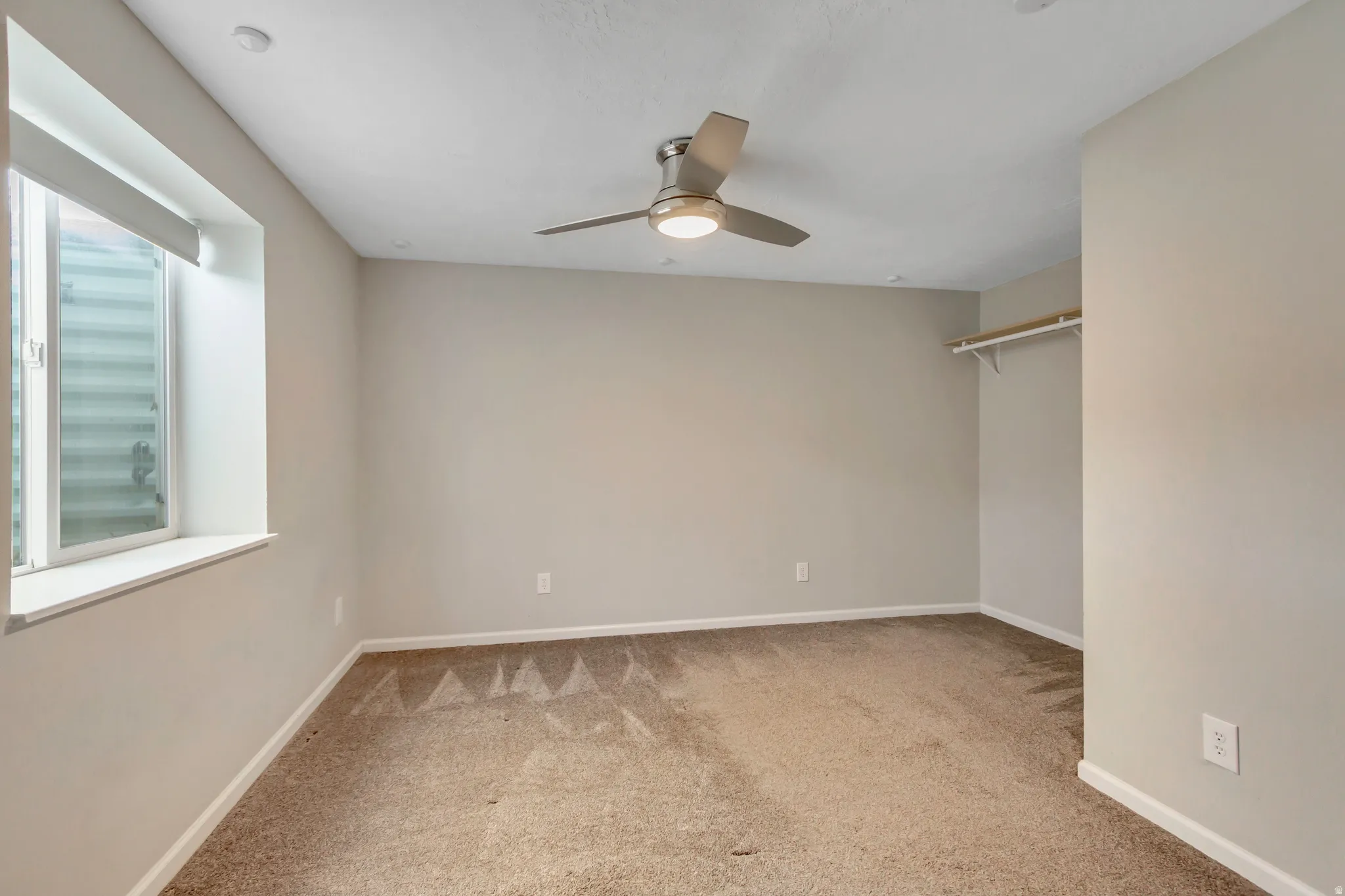 Carpeted room featuring neutral wall tones, a ceiling fan with integrated lighting, a recessed ceiling light, and a window with a deep sill