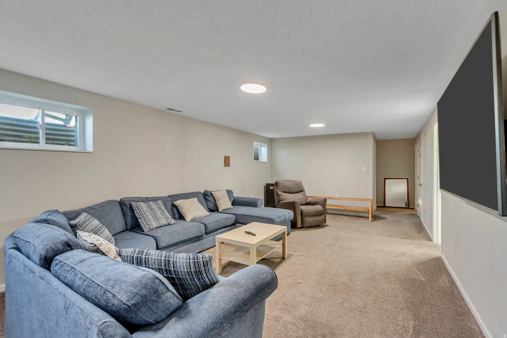 Spacious entertainment area featuring neutral-toned walls, recessed lighting, and a large window