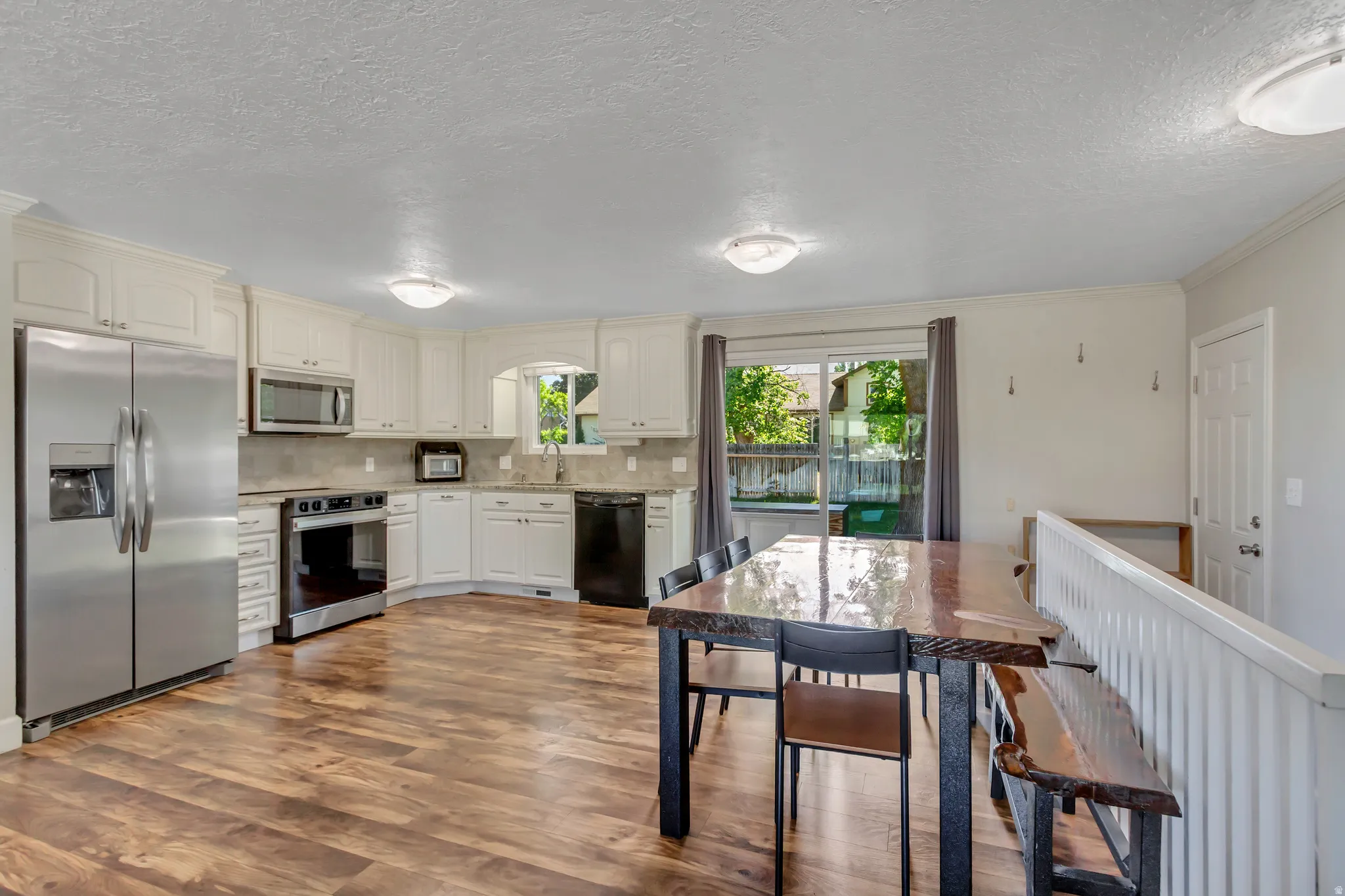 Open concept kitchen featuring cream-colored cabinetry, stainless steel appliances, wood-finish flooring, and a sliding glass door