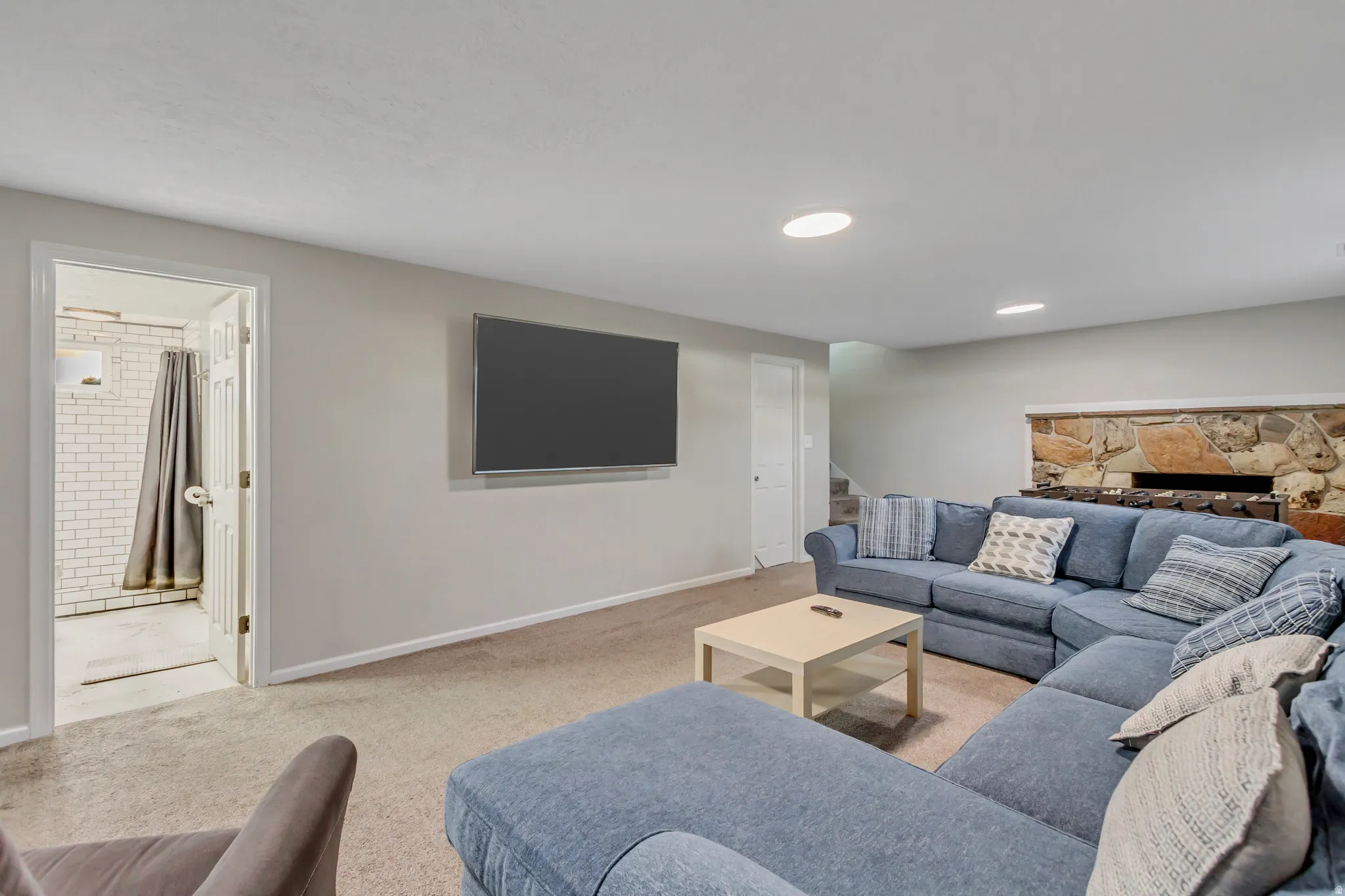 Carpeted recreation room featuring a stone-clad fireplace and recessed lighting