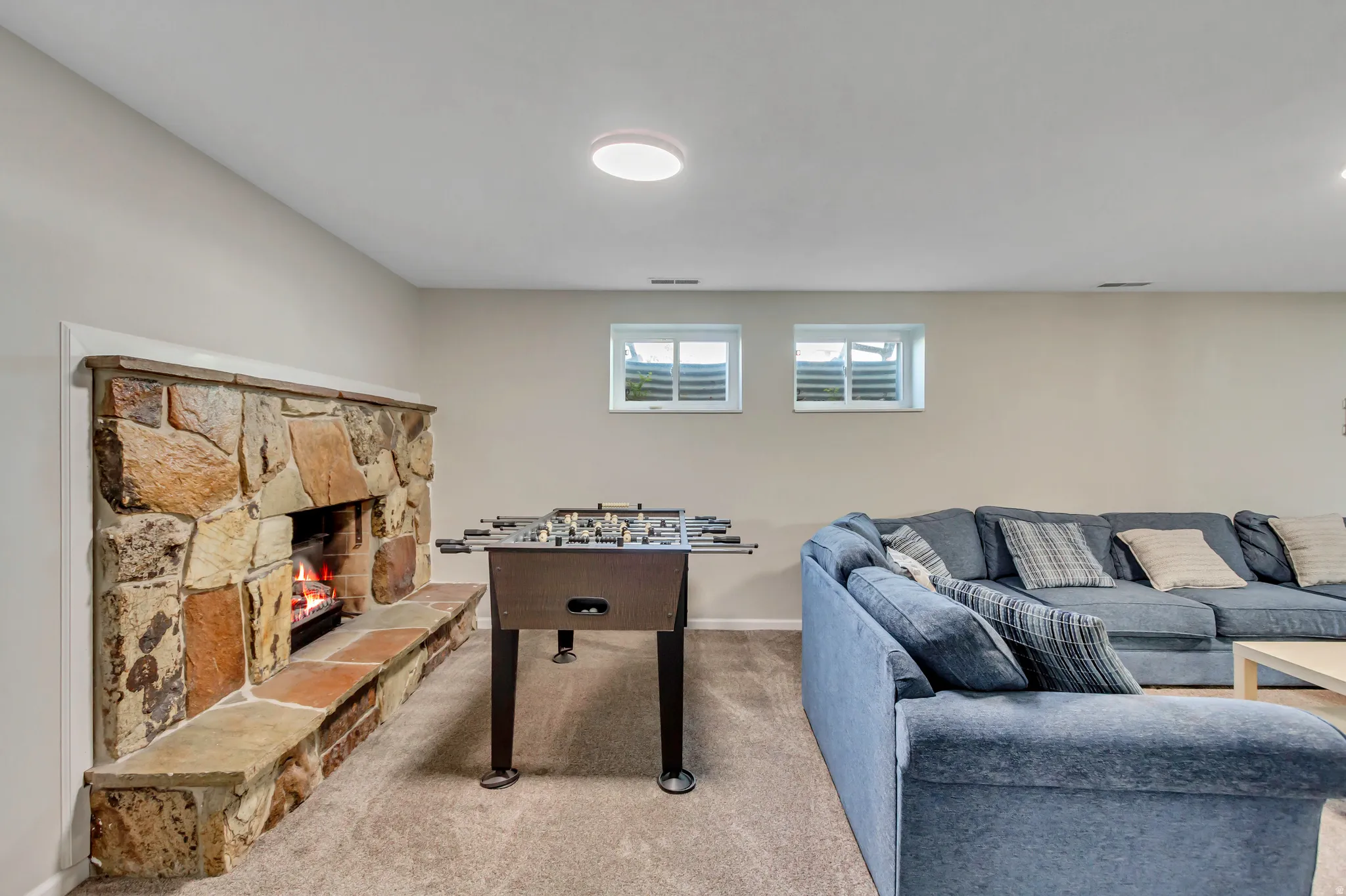 Stone fireplace with an extended hearth, recessed lighting, and soft carpet flooring