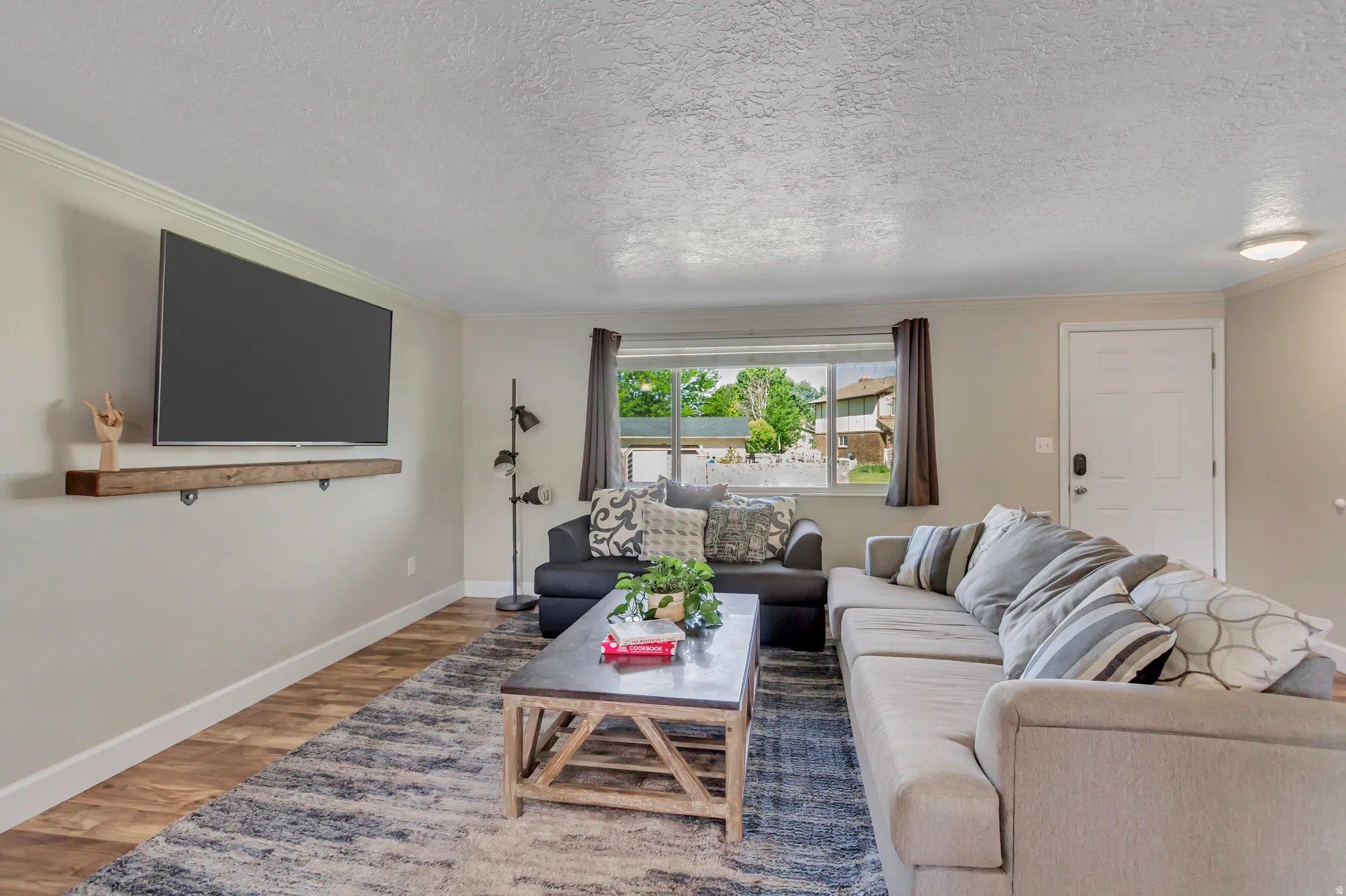 Spacious living area featuring wood-finish flooring, light neutral wall tones, and crown molding