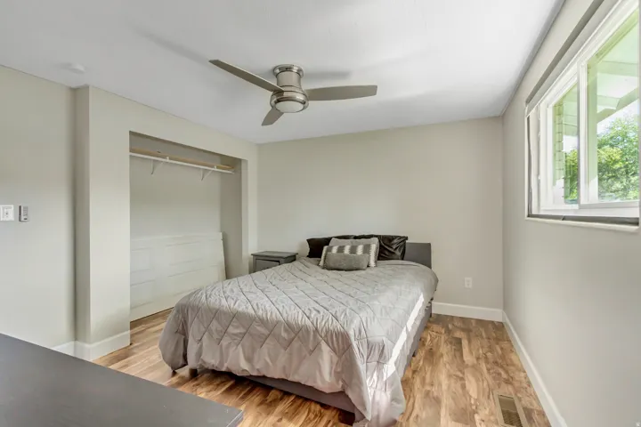 Bedroom featuring wood-finish flooring, a ceiling fan, and a built-in closet with shelving and hanging rod