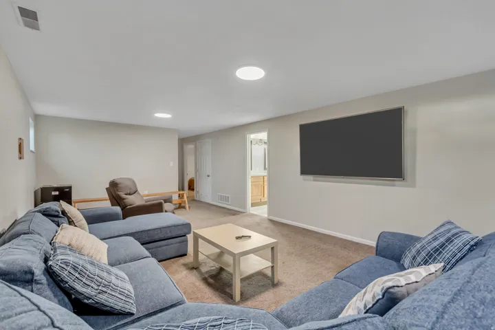 Spacious room featuring neutral wall paint, carpet flooring, a wall-mounted display, and recessed lighting