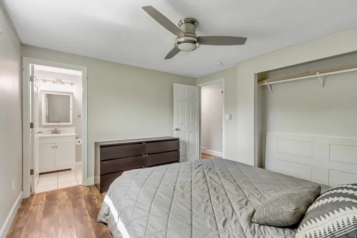 Bedroom featuring wood-finish flooring, a ceiling fan with integrated lighting, and an open closet with shelving and hanging rod
