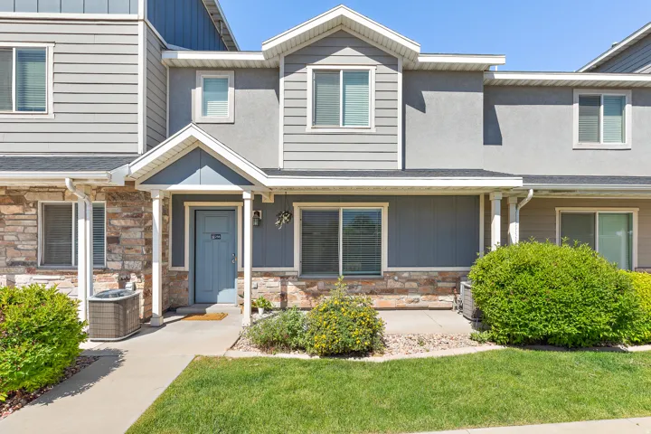 Townhome exterior featuring a blue entry door, stone veneer accents, and gray siding