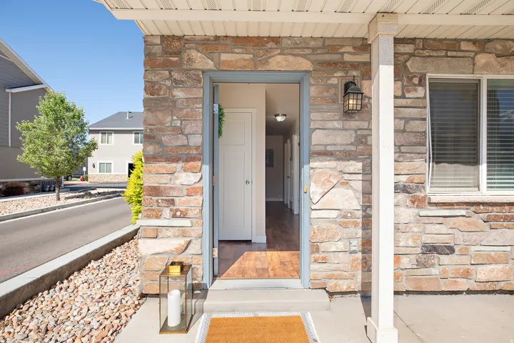 Stone veneer exterior featuring a covered entry, an exterior light fixture, and a white framed window