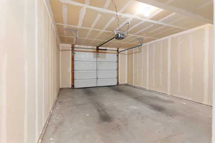 Spacious garage featuring a concrete floor, an overhead door with an automatic opener, and unfinished drywall walls and ceiling