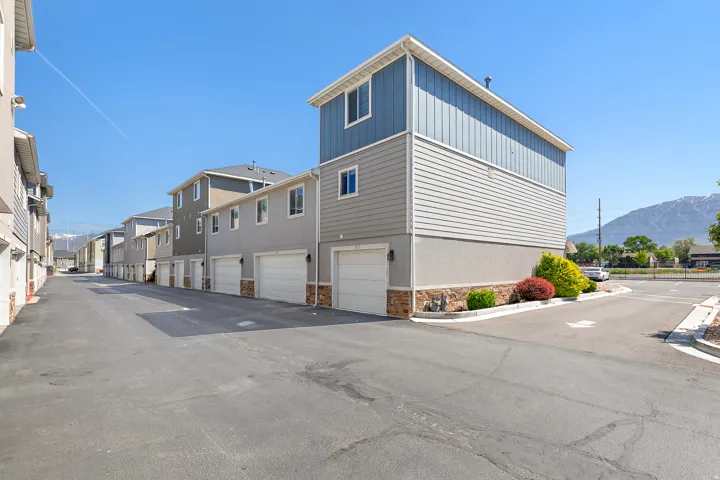 Multi-story townhome featuring blue vertical siding, gray horizontal siding, and a stone veneer foundation