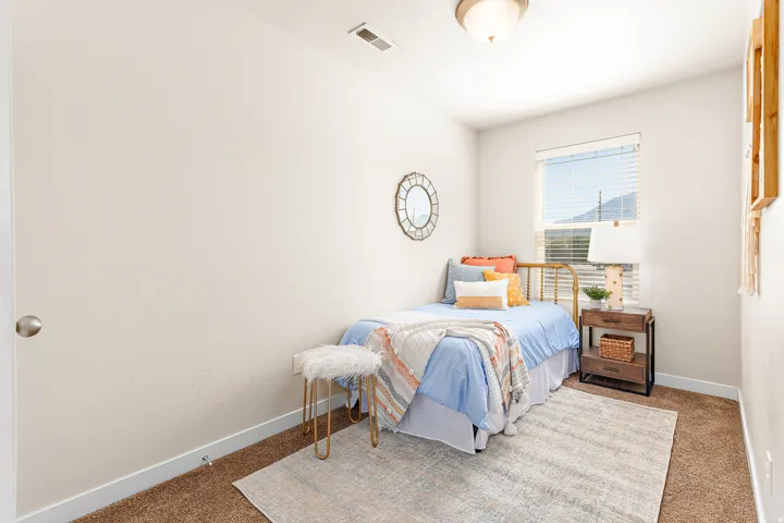 Neutral wall finishes and brown carpeting featuring a single window with horizontal blinds and a mountain backdrop