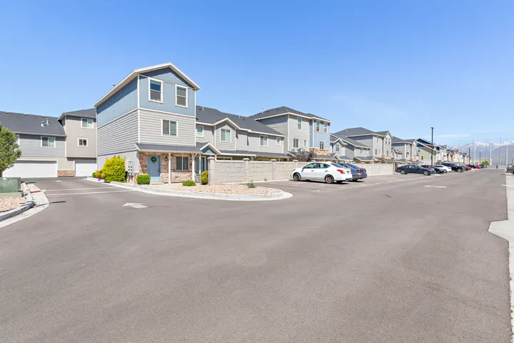Two-story townhome featuring blue and gray siding, stone veneer accents, an inviting front porch, and a dedicated garage space