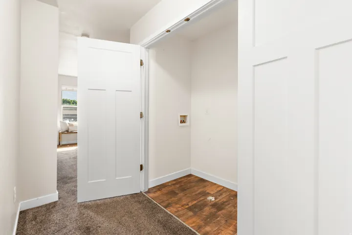 Dedicated laundry area featuring wood-finish flooring, white walls, and hookups for appliances