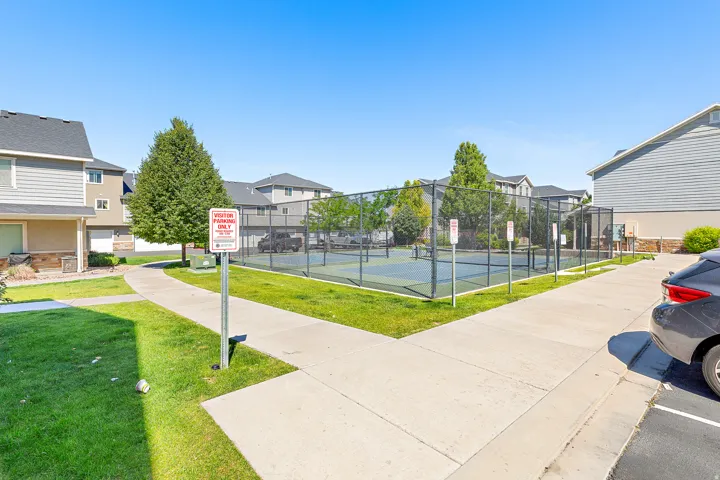 Recreational sports court with chain-link fencing, surrounded by mature trees and manicured lawns